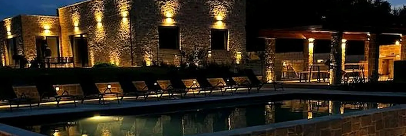 Stone villa and pool lit at night in Le Marche, Italy