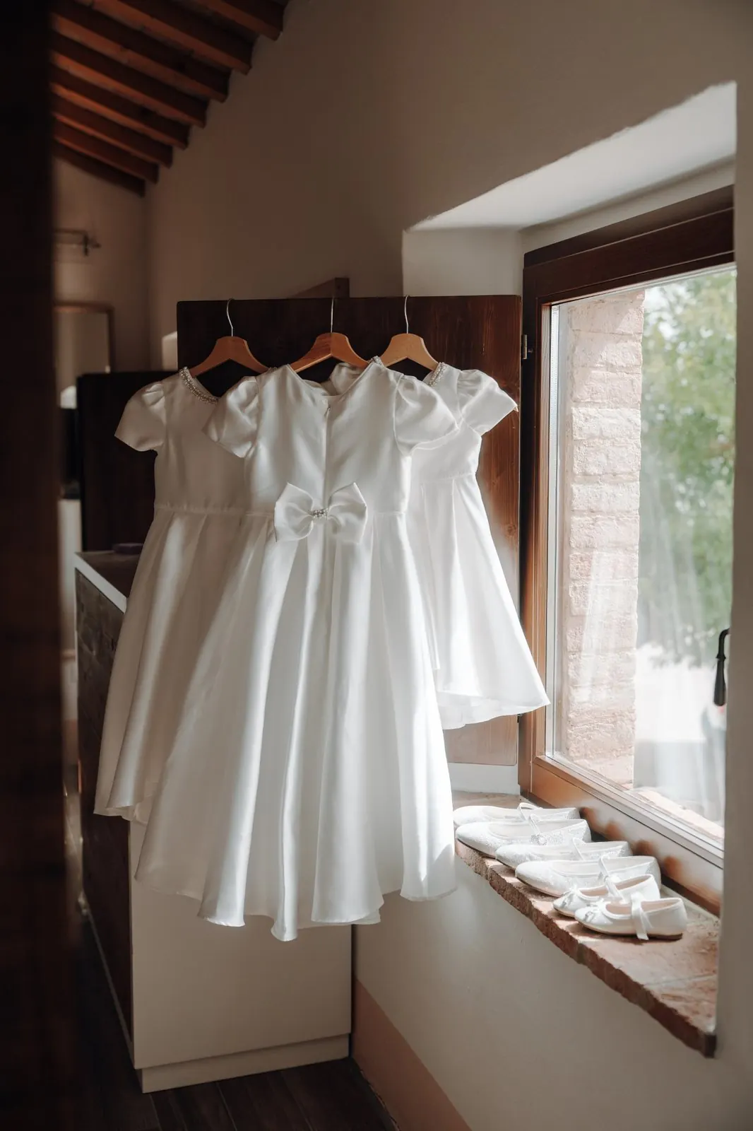 Flower girl dresses and shoes by a window in an Italian villa