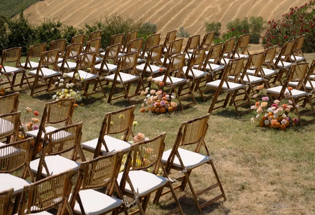 Ceremony chairs and flowers facing golden wheat fields in Le Marche