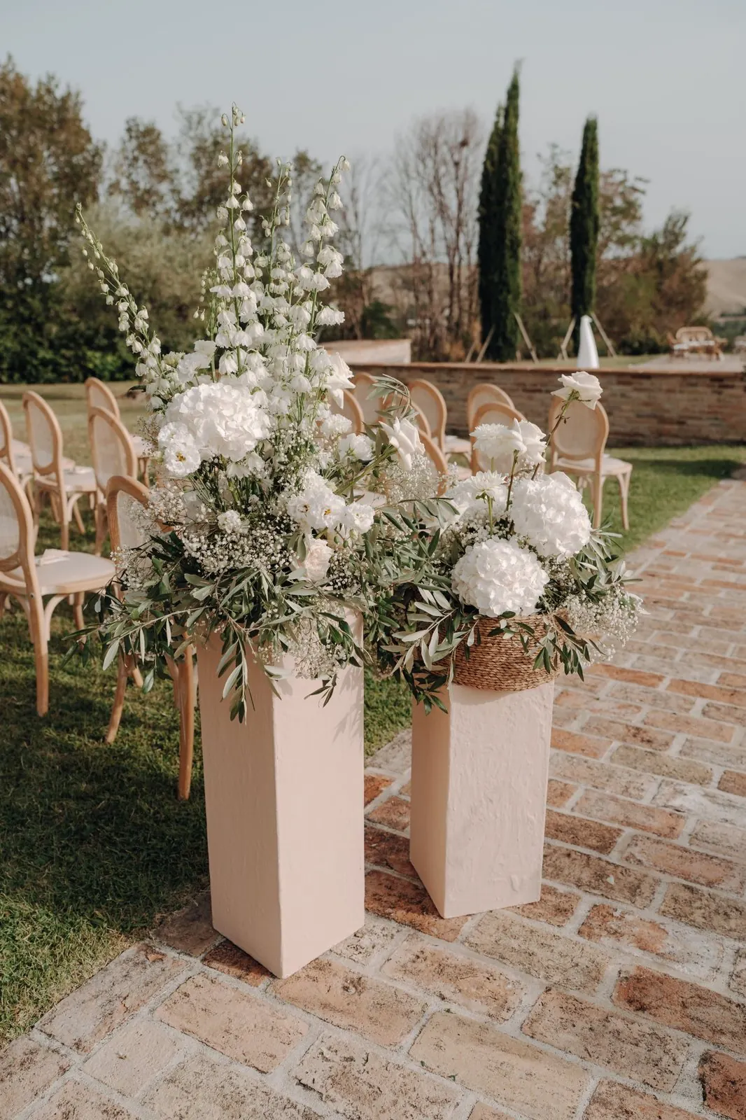 White hydrangeas, delphiniums and olive branches lining a ceremony aisle