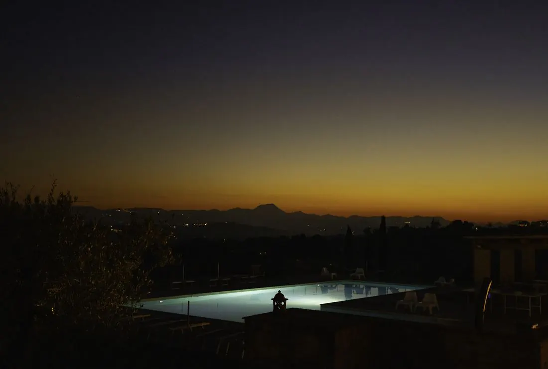 A villa pool at nightfall over the hills of Le Marche